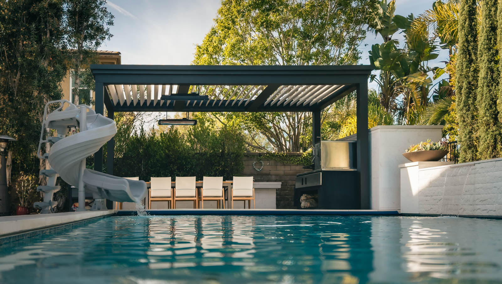 California pergola installed poolside next to freestanding pergola with seating area.