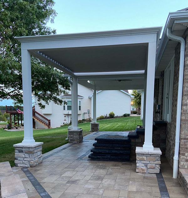 White pergola with stone pillars and fire feature