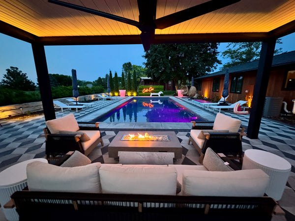 Black pergola by pool with warm lighting