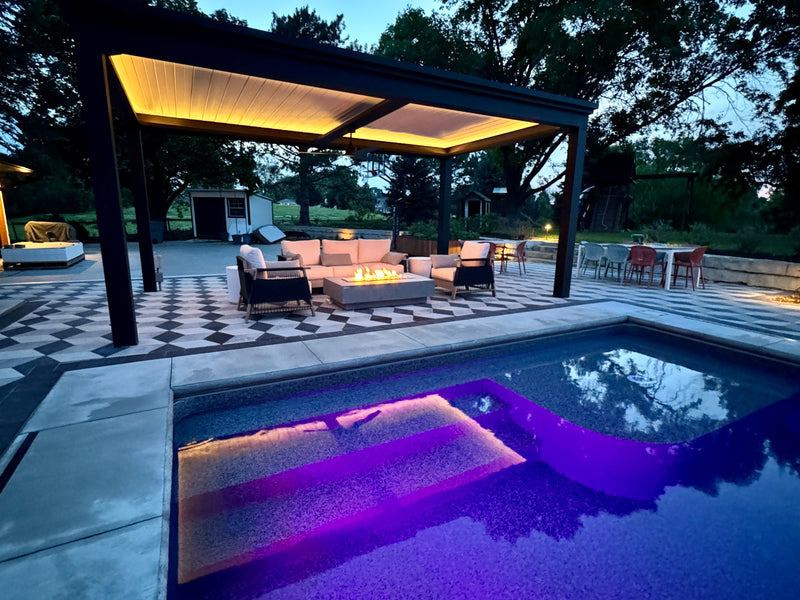 Black pergola with LED interior lighting over pool with purple-lit water