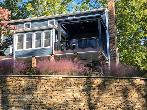 Black aluminum pergola with tan louvered roof and motorized shades over outdoor lounge seating