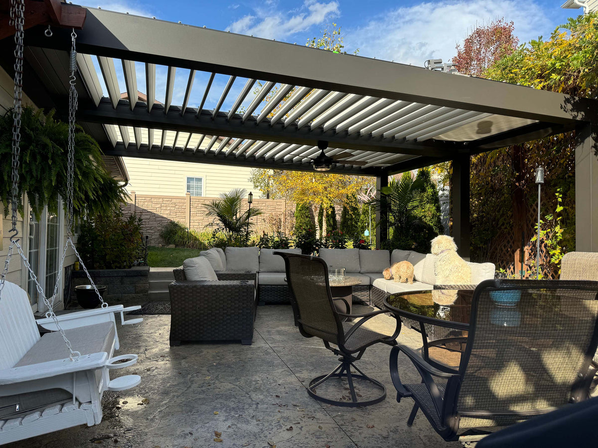 Gray and black aluminum pergola with louvered panels over log cabin patio with rustic railings