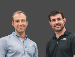 Two men standing side by side against a dark background