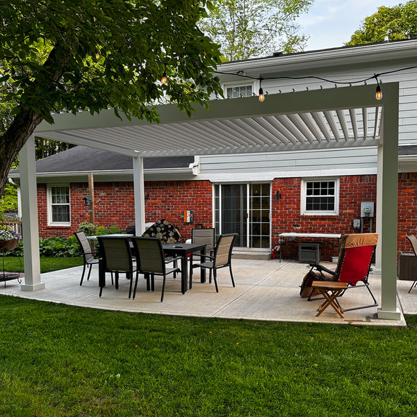 White pergola covering brick patio with dining table and shade leaves overhead