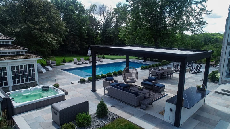 Backyard scene with black aluminum pergola over seating area, pool, and hot tub