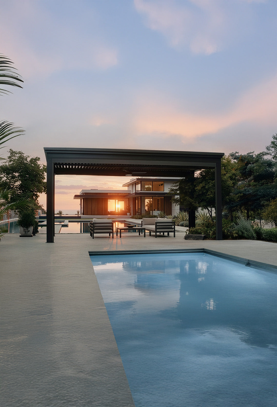 Pool area with a pergola and sunset in the background